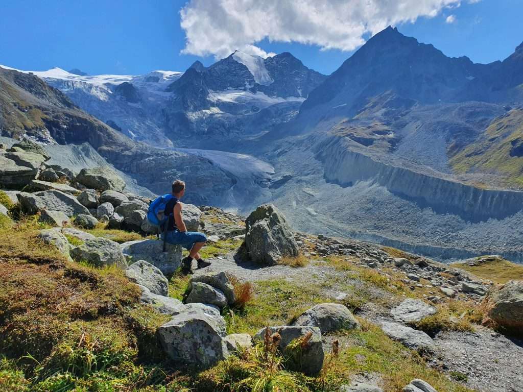 A hiker amidst the breathtaking glacier scenery of Swiss Alps in Anniviers, Switzerland.